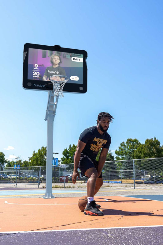 A basketball player dribbling away from the huupe