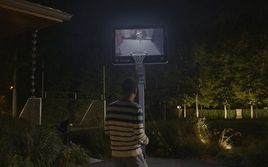 A basketball player looking at the huupe with the screen lit up on the backboard